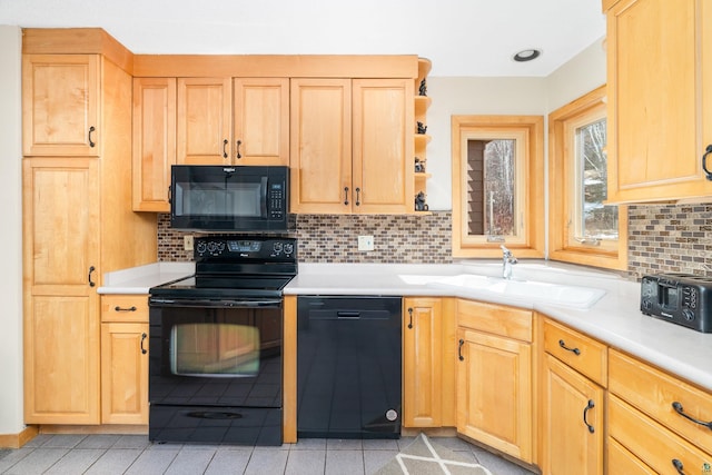 kitchen featuring light countertops, a sink, backsplash, and black appliances