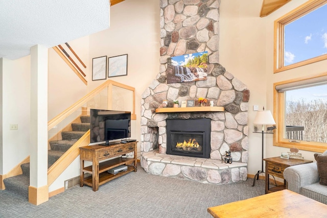 carpeted living room featuring stairway, baseboards, a towering ceiling, and a fireplace