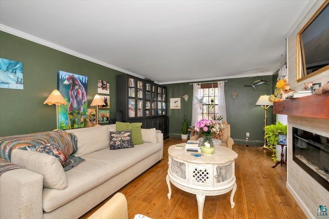 living room with a glass covered fireplace, baseboards, wood finished floors, and crown molding