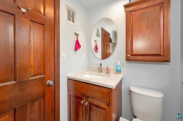 bathroom featuring visible vents, toilet, and vanity