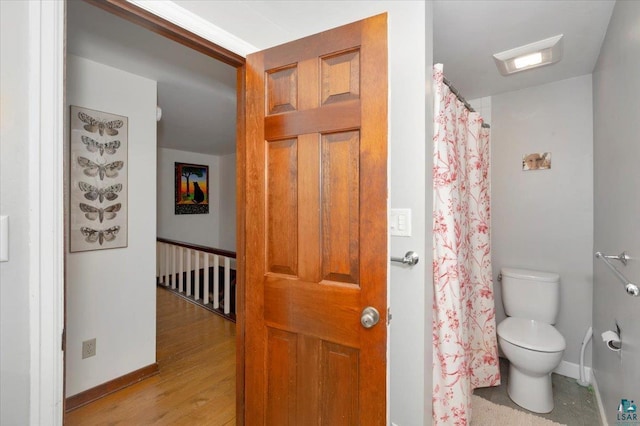 full bath featuring wood finished floors, baseboards, a shower with shower curtain, and toilet