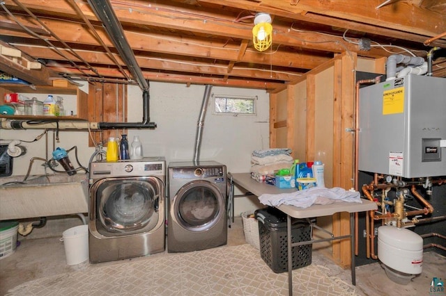 clothes washing area with washer and dryer, a sink, tankless water heater, and laundry area