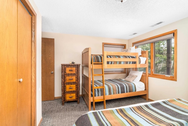 carpeted bedroom featuring baseboards, a textured ceiling, and visible vents