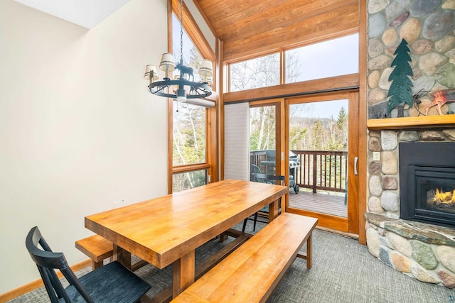 carpeted dining area featuring a fireplace, vaulted ceiling, and an inviting chandelier