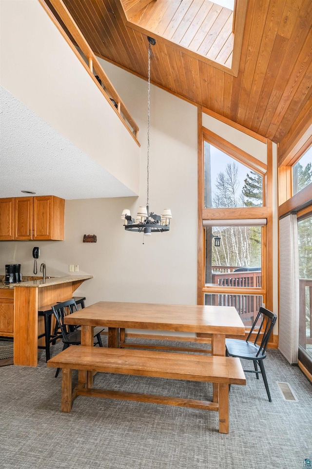 dining room featuring light colored carpet, wood ceiling, and an inviting chandelier