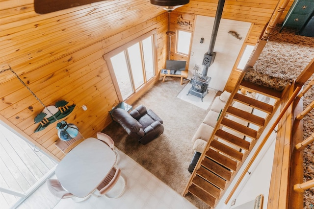 living area with wood walls, a wood stove, and carpet