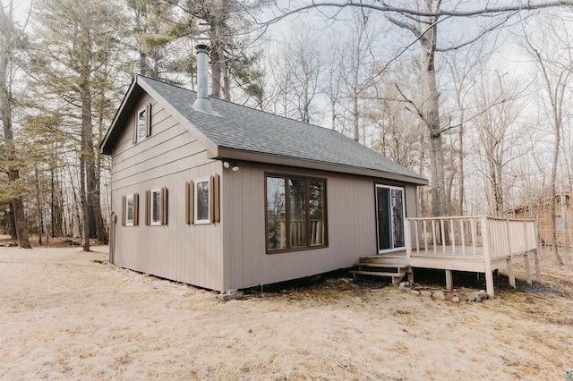 back of house with roof with shingles and a deck