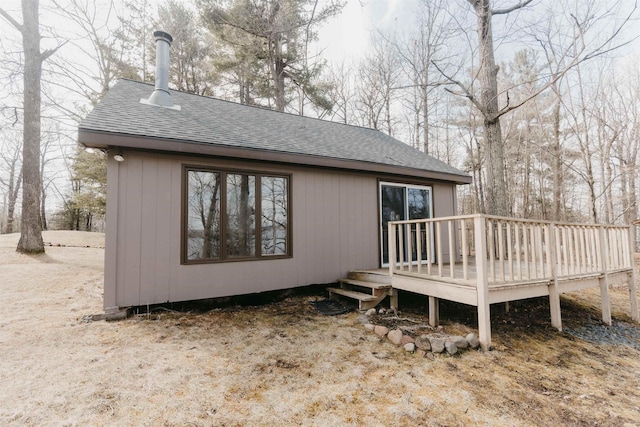 back of property with a shingled roof and a deck