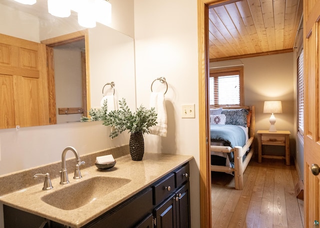 ensuite bathroom with wood ceiling, hardwood / wood-style flooring, vanity, connected bathroom, and ornamental molding