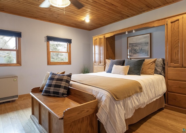 bedroom featuring radiator heating unit, light wood finished floors, wood ceiling, and multiple windows