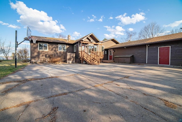 ranch-style home with a chimney, an outdoor structure, driveway, and a storage shed