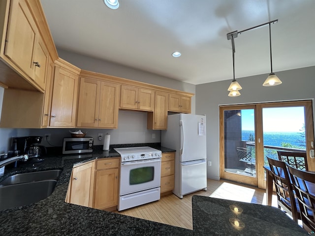 kitchen with dark stone counters, a sink, light brown cabinetry, white appliances, and decorative light fixtures
