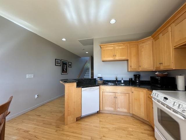 kitchen featuring a peninsula, a sink, recessed lighting, light wood-style floors, and white appliances