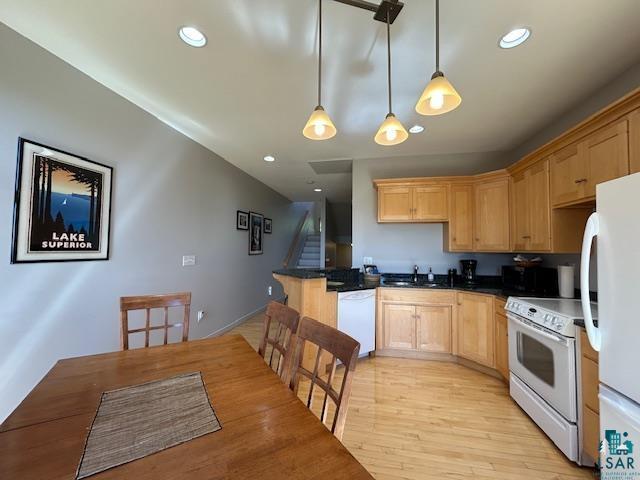 kitchen with light brown cabinets, a sink, white appliances, pendant lighting, and a peninsula