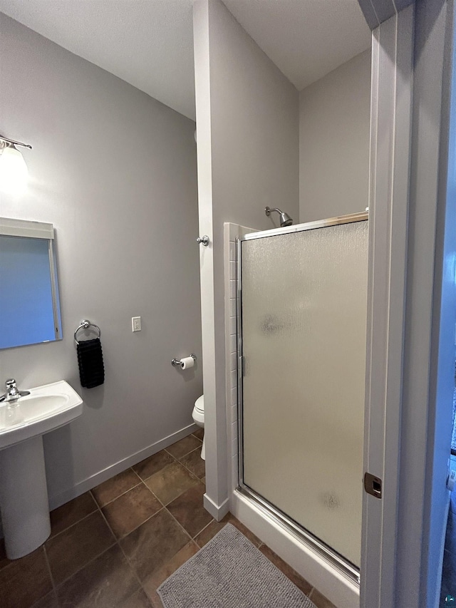 bathroom featuring a sink, toilet, baseboards, tile patterned flooring, and a shower stall
