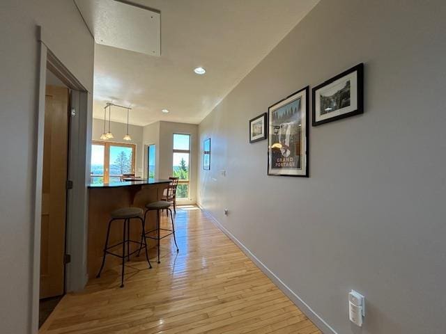 hallway featuring recessed lighting, light wood finished floors, and baseboards