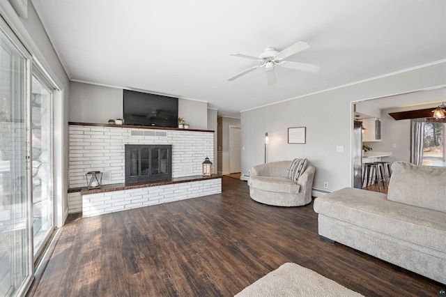 living area with crown molding, a ceiling fan, wood finished floors, and a fireplace