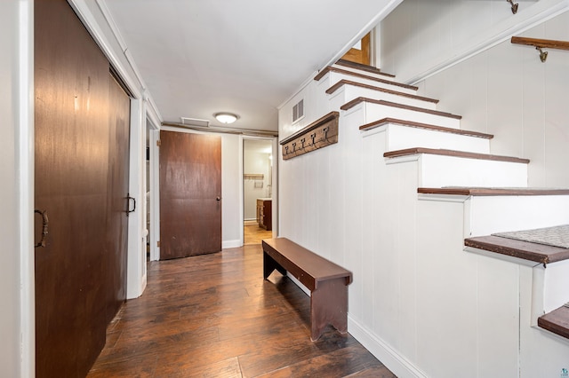 hall with wood finished floors, visible vents, and baseboards