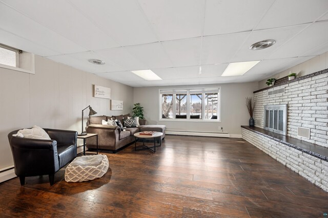 living room with a drop ceiling, visible vents, baseboard heating, hardwood / wood-style flooring, and a fireplace