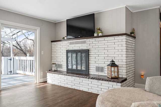 living area featuring visible vents, baseboards, wood finished floors, a fireplace, and ornamental molding
