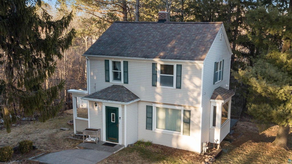 view of front of home with a chimney and roof with shingles