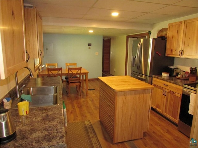 kitchen featuring a sink, wood counters, stainless steel appliances, a center island, and wood finished floors