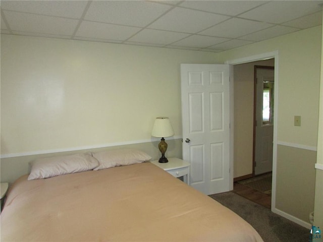 bedroom with a paneled ceiling, dark carpet, and baseboards