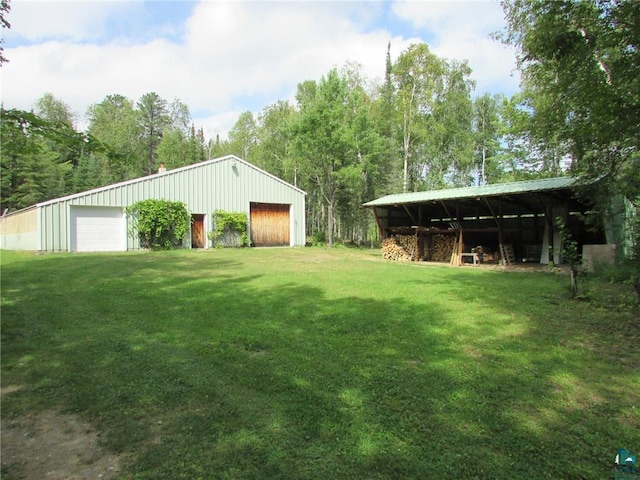 view of yard featuring an outdoor structure, a pole building, and a detached garage
