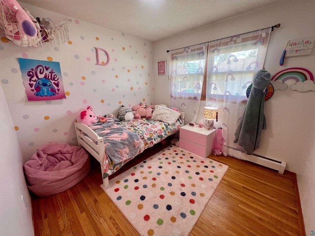 bedroom featuring wood finished floors and a baseboard radiator