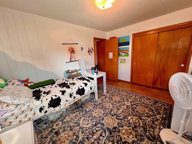 bedroom featuring wood finished floors, a textured ceiling, and a closet