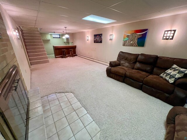 carpeted living area featuring a dry bar, a paneled ceiling, stairs, and a baseboard radiator