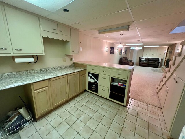 kitchen featuring light tile patterned floors, light countertops, open floor plan, a drop ceiling, and a peninsula