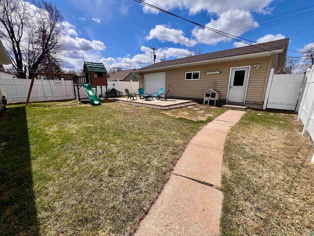 back of house featuring a lawn, a fenced backyard, a patio area, and a playground