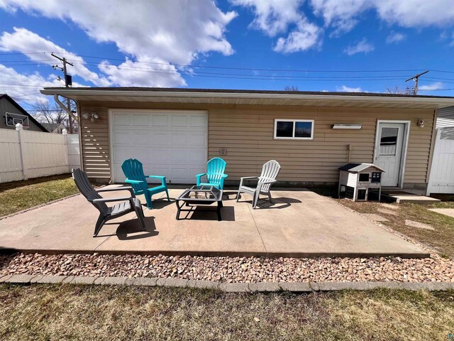 back of property featuring a patio area, a garage, a fire pit, and fence