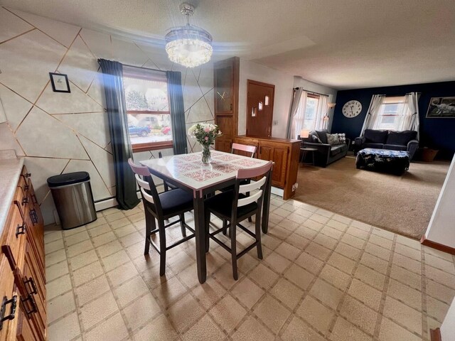 dining area with a chandelier, light floors, light colored carpet, and a baseboard heating unit