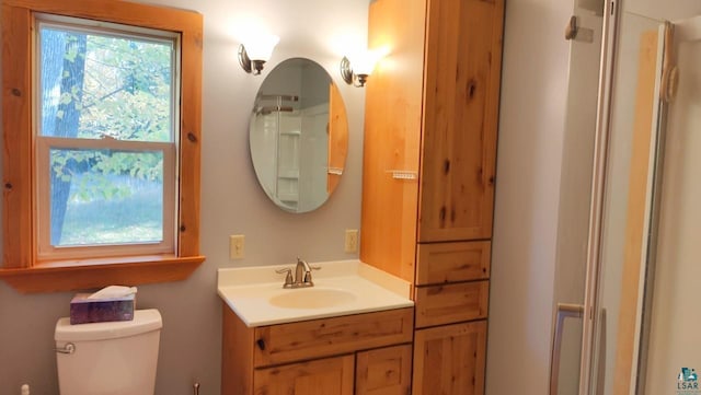 bathroom featuring toilet, walk in shower, and vanity