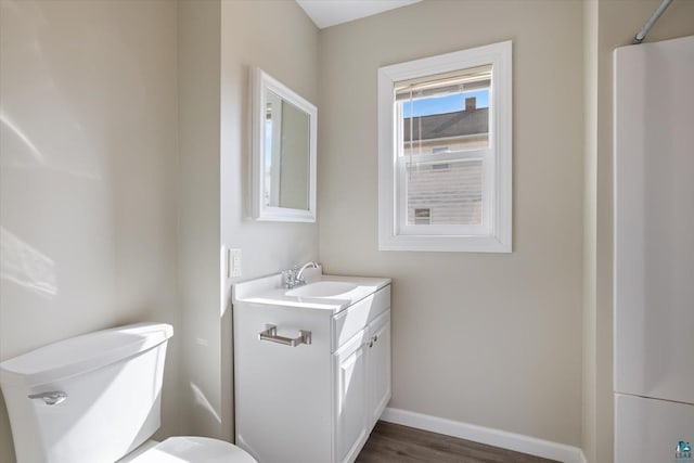 bathroom with wood finished floors, vanity, toilet, and baseboards