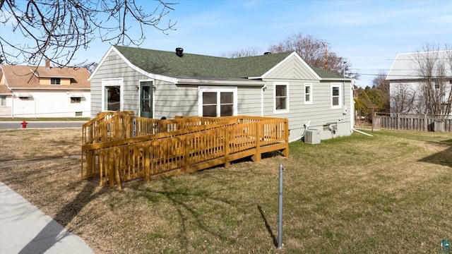 back of house featuring a deck, fence, central air condition unit, roof with shingles, and a lawn