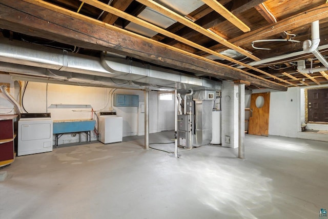below grade area featuring heating unit, a sink, and washer / clothes dryer