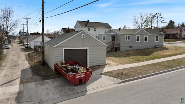 view of front of home featuring a front yard, crawl space, a garage, an outdoor structure, and a residential view