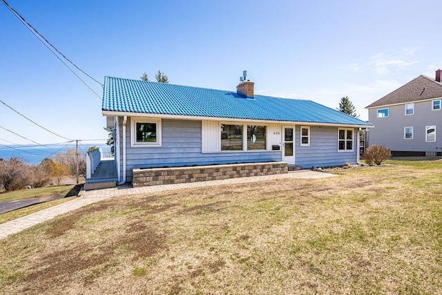 view of front of property with a tiled roof, a chimney, and a front lawn