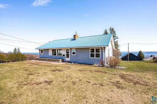 back of house featuring a lawn and a chimney