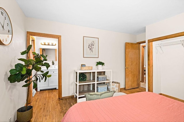 bedroom with baseboards, wood finished floors, and ensuite bathroom