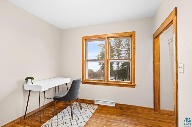 home office featuring baseboards, a baseboard heating unit, wood finished floors, and visible vents