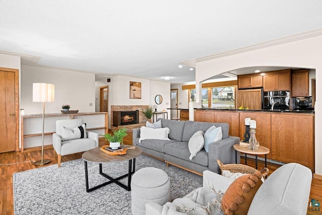 living area with a brick fireplace, recessed lighting, arched walkways, and wood finished floors