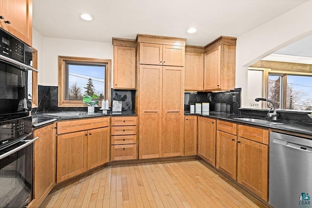 kitchen featuring plenty of natural light, a sink, light wood finished floors, and black appliances
