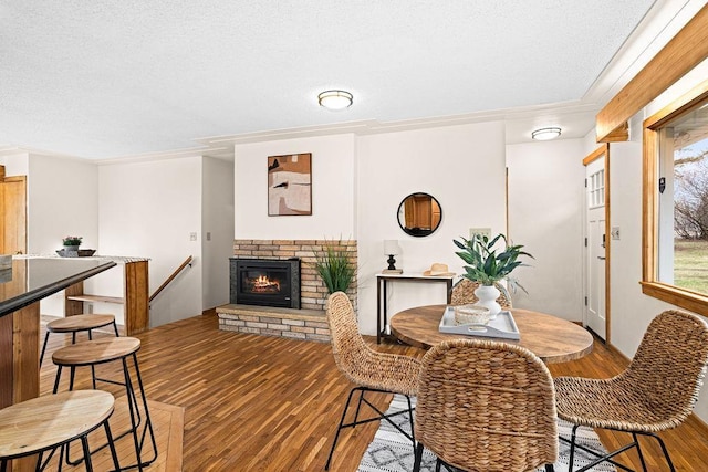 dining room featuring crown molding, a textured ceiling, wood finished floors, and a fireplace