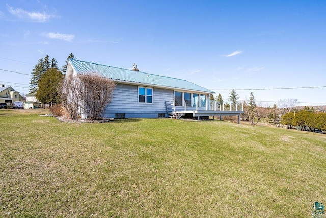 back of house featuring a lawn, a chimney, and metal roof