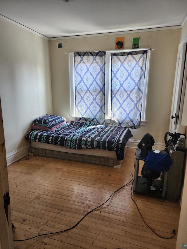 bedroom featuring hardwood / wood-style flooring, crown molding, and baseboards