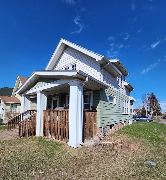 view of side of home with a lawn and covered porch